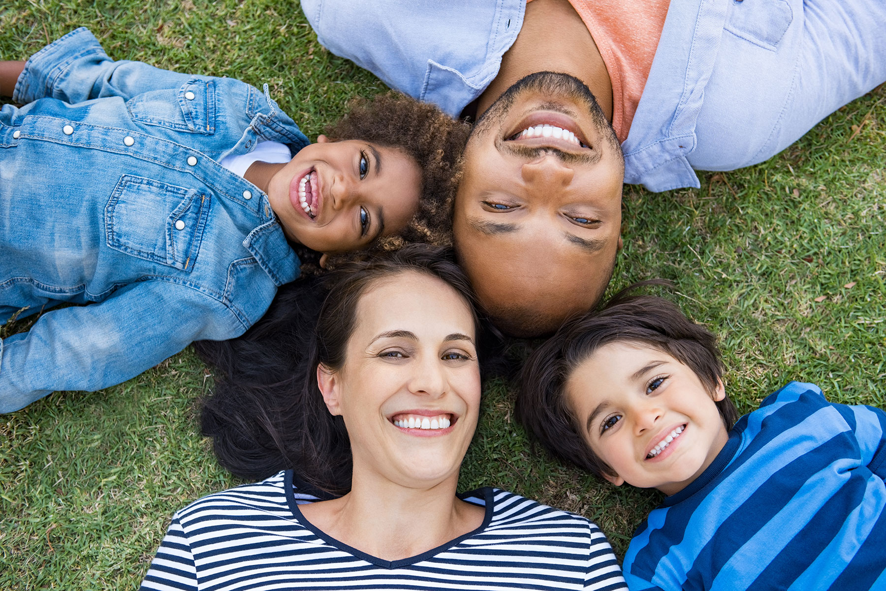 Family lying in the grass and smiling