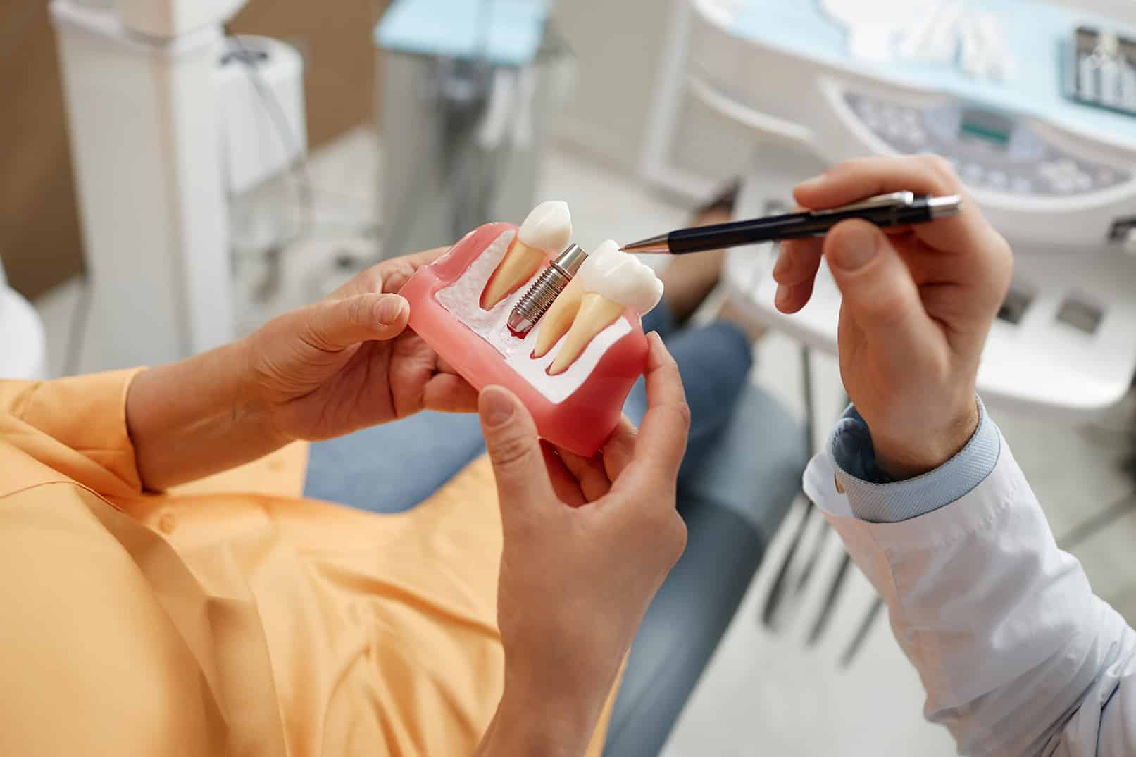 dr harris pointing to a dental implant restoration model during consultation at denter ridge dental professionals